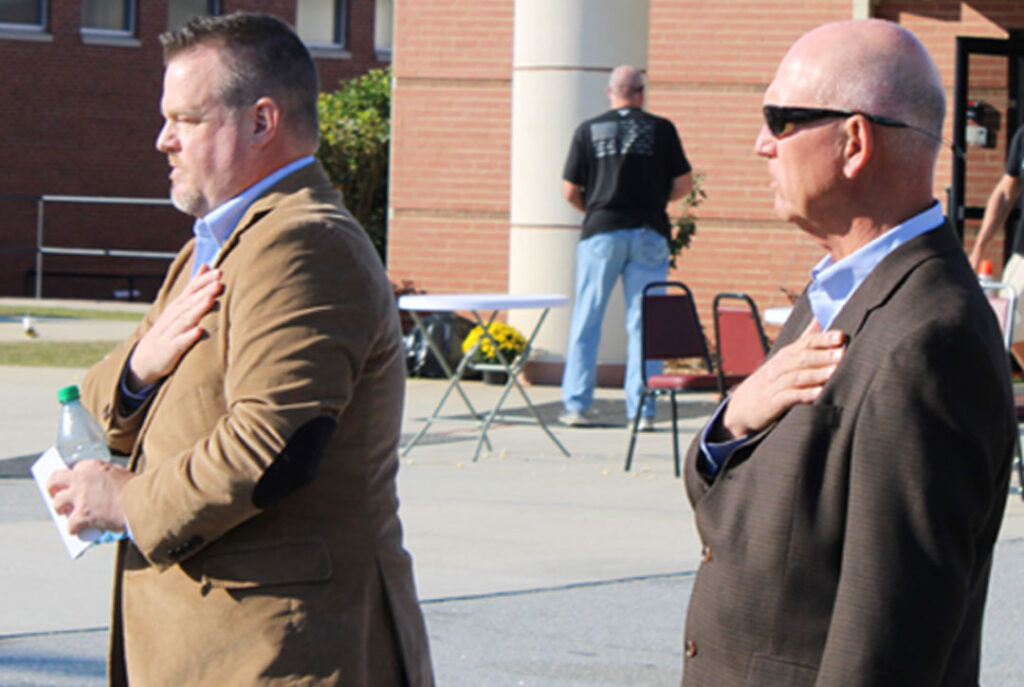 Travis McAlister, Pastor of Golden Creek Baptist Church in Liberty, and State Senator Rex Rice during the national anthem (Photo by Karen Brewer, The Pickens County Chronicle)