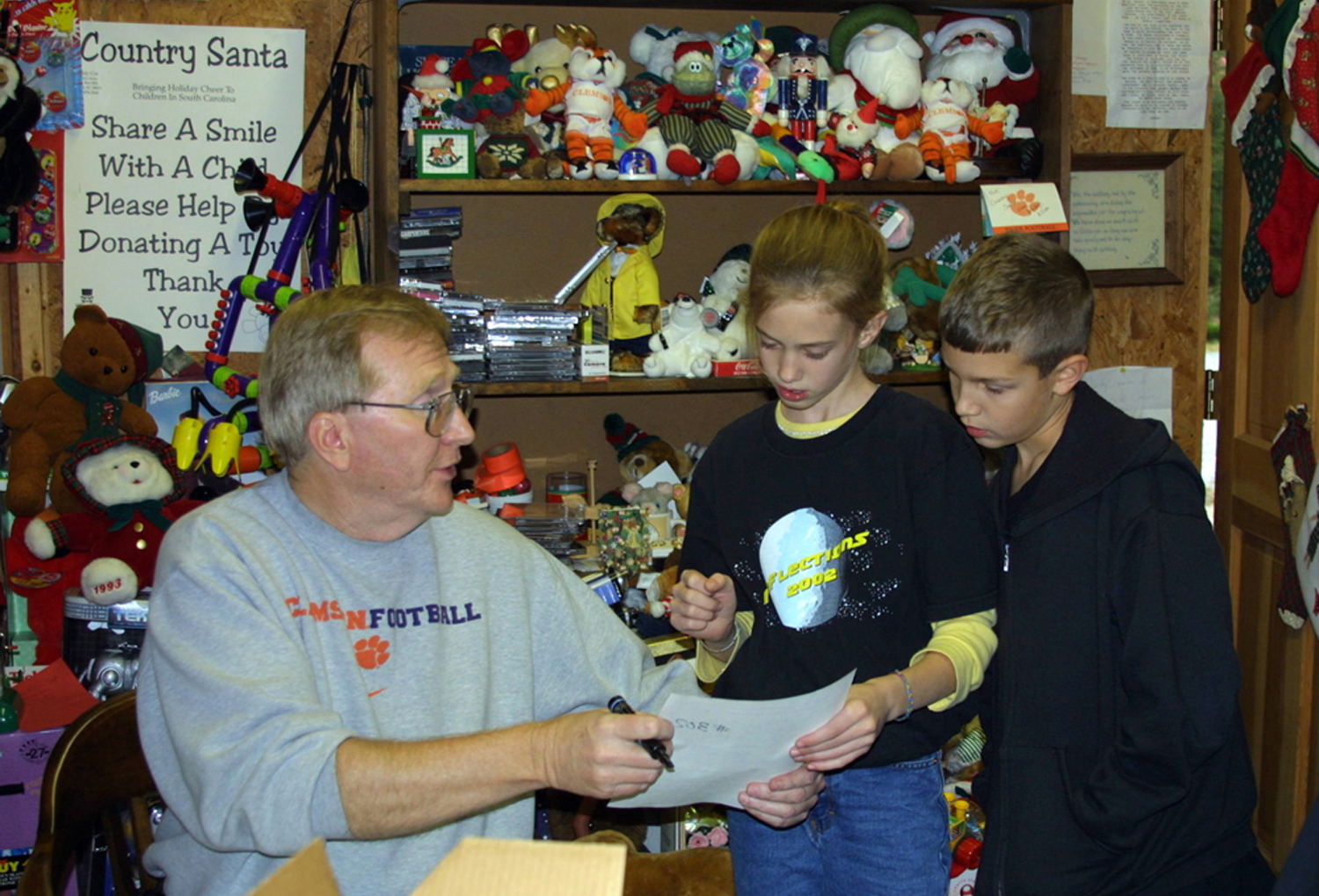 Buddy Cox (Country Santa) is assisted by two young volunteers. (Photo courtesy of Bob Spalding)