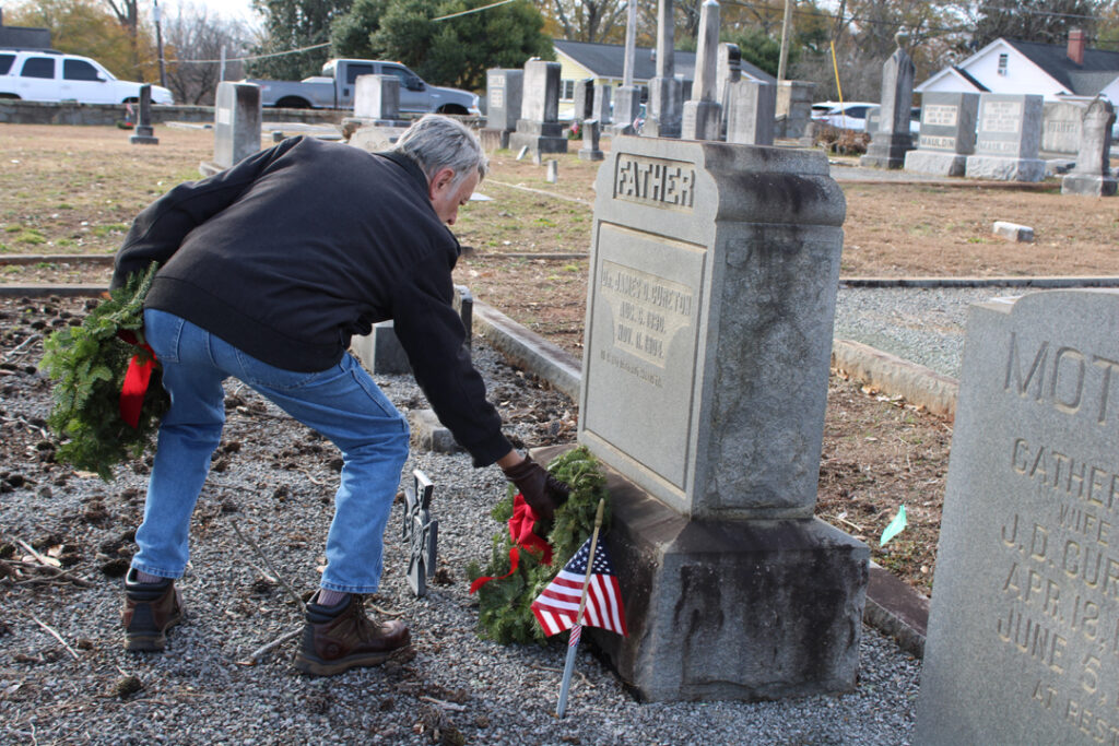 Wayne Kelley, Senior Vice President of the Pickens County Historical Society, lays a wreath on a veteran's grave. (Photo by Karen Brewer, The Pickens County Chronicle)