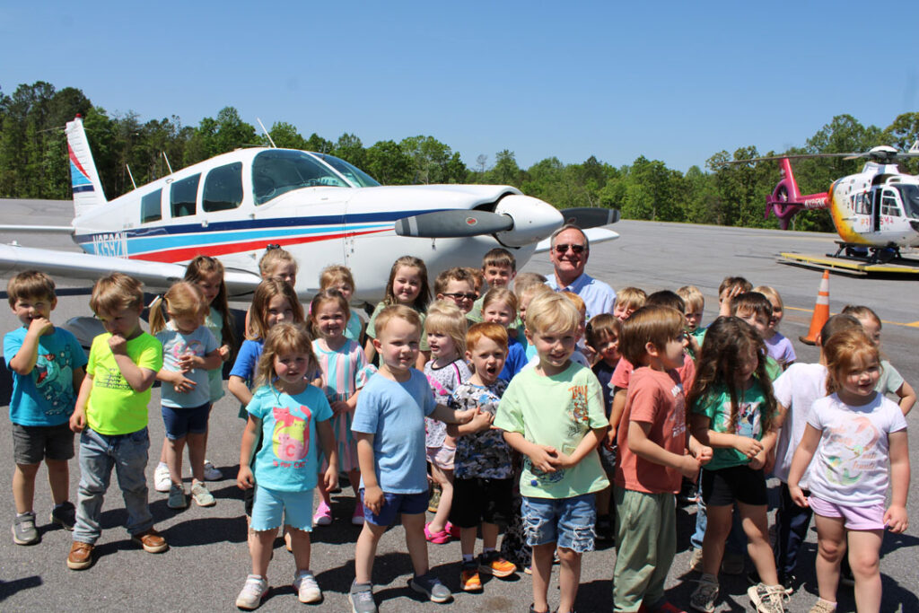 South Carolina Aeronautics District 3 Commissioner Skeets Cooper, of Pickens, with children from Dacusville Elementary School's three-year-old and four-year-old kindergarten classes at the Pickens County Airport in Liberty on Monday, April 28, 2025. (Photo by Karen Brewer, The Pickens County Chronicle)