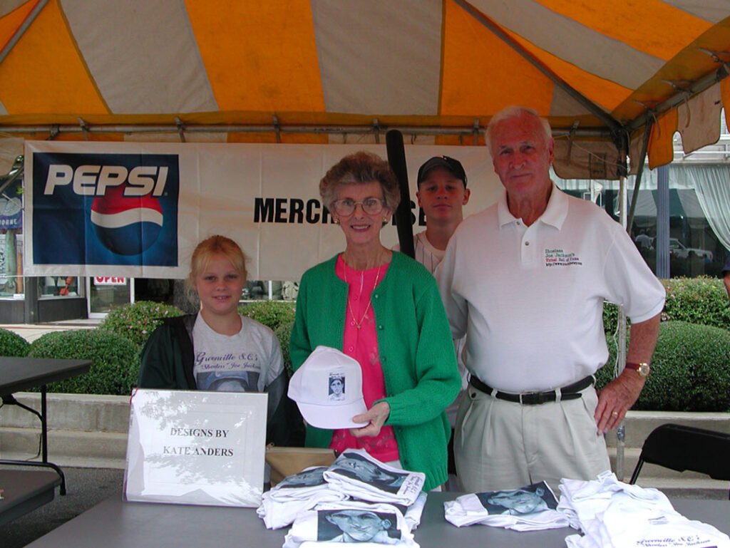 Joe and Kate Anders with granddaughter Erin and grandson Joe on July 13, 2002, the day of the 'Shoeless' Joe Jackson statue unveiling in Greenville, with Kate's artwork depicting the likeness of 'Shoeless' Joe Jackson on t-shirts and caps. (Photo by Karen Brewer)