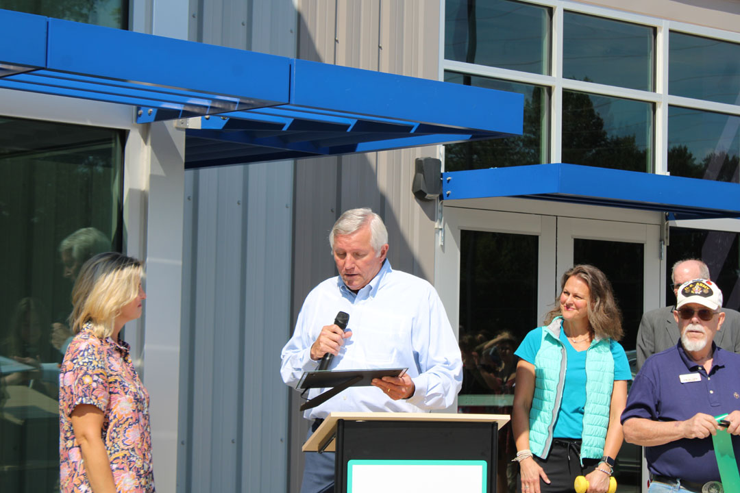 Rick Cothran, Director of Membership and Engagement with the Easley Chamber of Commerce, presents Kim Valentin with a gift of $1 from the Easley Chamber of Commerce. (Photo by Karen Brewer, The Pickens County Chronicle)
