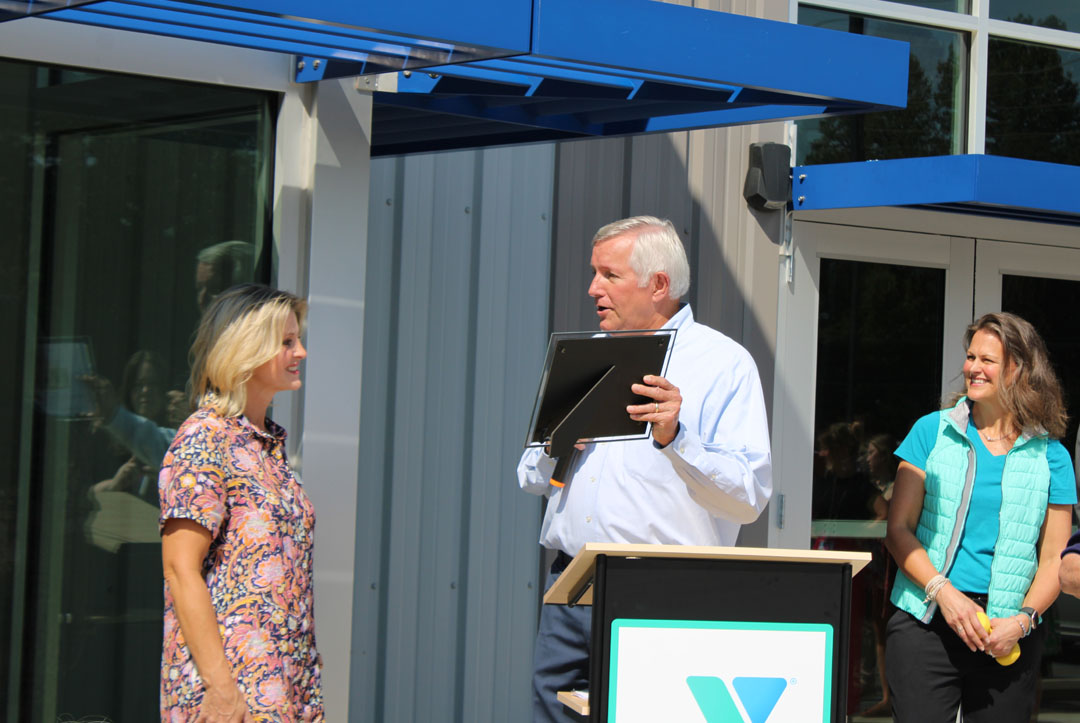 Rick Cothran, Director of Membership and Engagement with the Easley Chamber of Commerce, presents Kim Valentin with a gift of $1 from the Easley Chamber of Commerce. (Photo by Karen Brewer, The Pickens County Chronicle)
