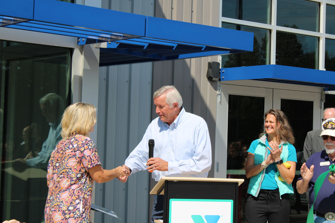 Rick Cothran, Director of Membership and Engagement with the Easley Chamber of Commerce, presents Kim Valentin with a gift of $1 from the Easley Chamber of Commerce. (Photo by Karen Brewer, The Pickens County Chronicle)