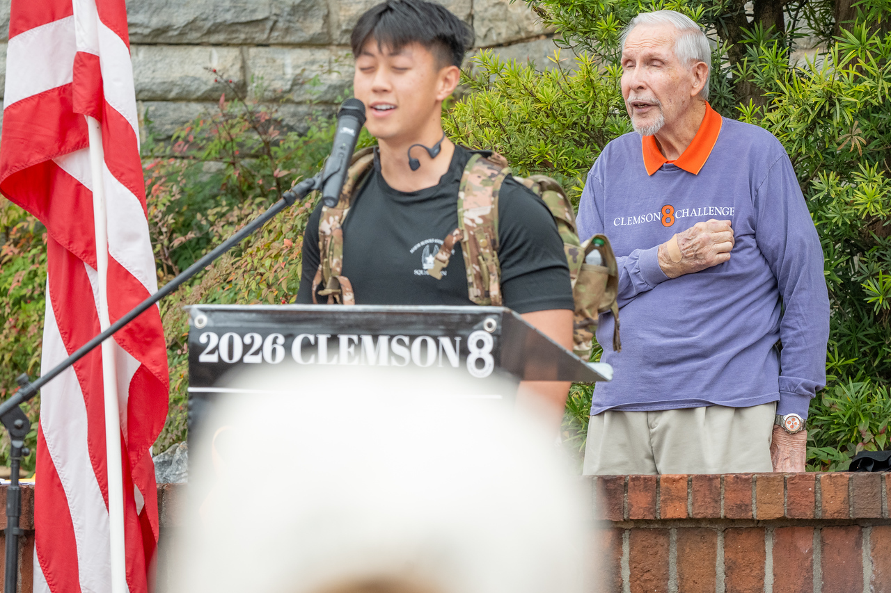Hundreds of people participate in the 2026 Clemson 8 Challenge, an eight-mile run/walk/ruck march, on a misty Saturday morning, March 7, 2026. The Challenge was created to honor the 25 known Clemson alumni who suffered as POWs in all wars. It was originally created for 1938 Clemson alumnus, professor emeritus and WWII hero Ben Skardon, a survivor of the Bataan Death March, but has expanded to include Clemson POWs from all wars. Money raised from the event goes toward sending teams of Clemson ROTC students to participate in the Bataan Memorial Death March at White Sands Missile Range, NM. Sophomore finance major GB Stalnaker served as master of ceremonies. (Photo by Ken Scar)
