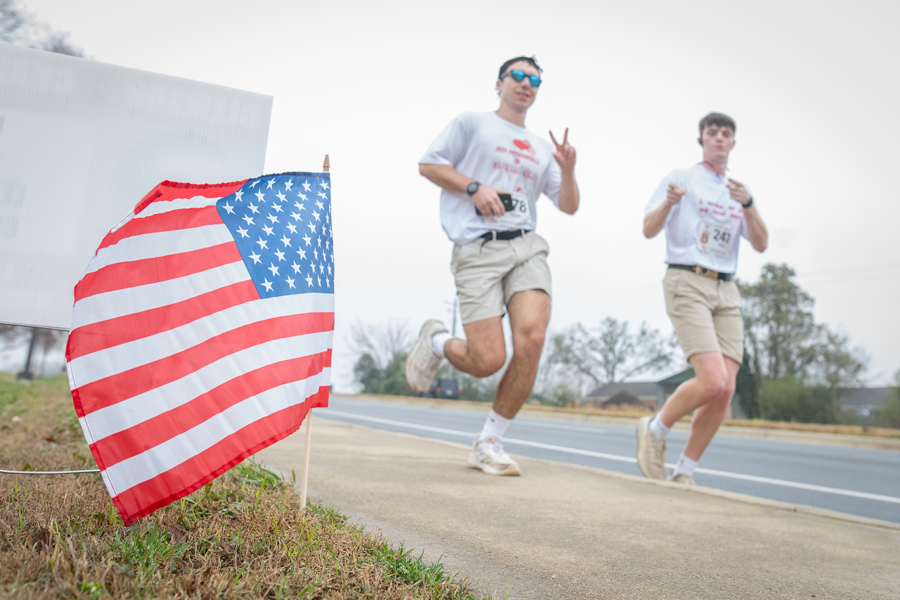 Hundreds of people participate in the 2026 Clemson 8 Challenge, an eight-mile run/walk/ruck march, on a misty Saturday morning, March 7, 2026. The Challenge was created to honor the 25 known Clemson alumni who suffered as POWs in all wars. It was originally created for 1938 Clemson alumnus, professor emeritus and WWII hero Ben Skardon, a survivor of the Bataan Death March, but has expanded to include Clemson POWs from all wars. Money raised from the event goes toward sending teams of Clemson ROTC students to participate in the Bataan Memorial Death March at White Sands Missile Range, NM. Sophomore finance major GB Stalnaker served as master of ceremonies. (Photo by Ken Scar)