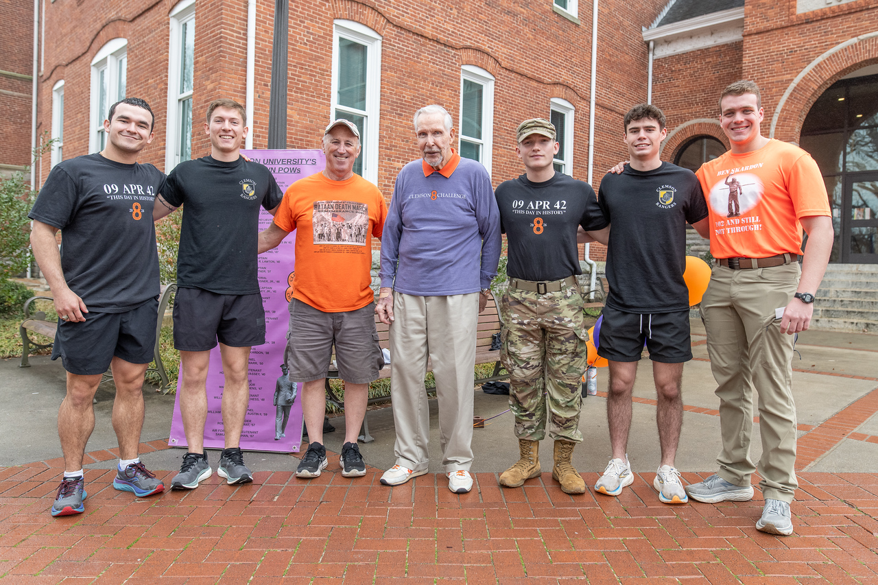 Hundreds of people participate in the 2026 Clemson 8 Challenge, an eight-mile run/walk/ruck march, on a misty Saturday morning, March 7, 2026. The Challenge was created to honor the 25 known Clemson alumni who suffered as POWs in all wars. It was originally created for 1938 Clemson alumnus, professor emeritus and WWII hero Ben Skardon, a survivor of the Bataan Death March, but has expanded to include Clemson POWs from all wars. Money raised from the event goes toward sending teams of Clemson ROTC students to participate in the Bataan Memorial Death March at White Sands Missile Range, NM. Sophomore finance major GB Stalnaker served as master of ceremonies. (Photo by Ken Scar)