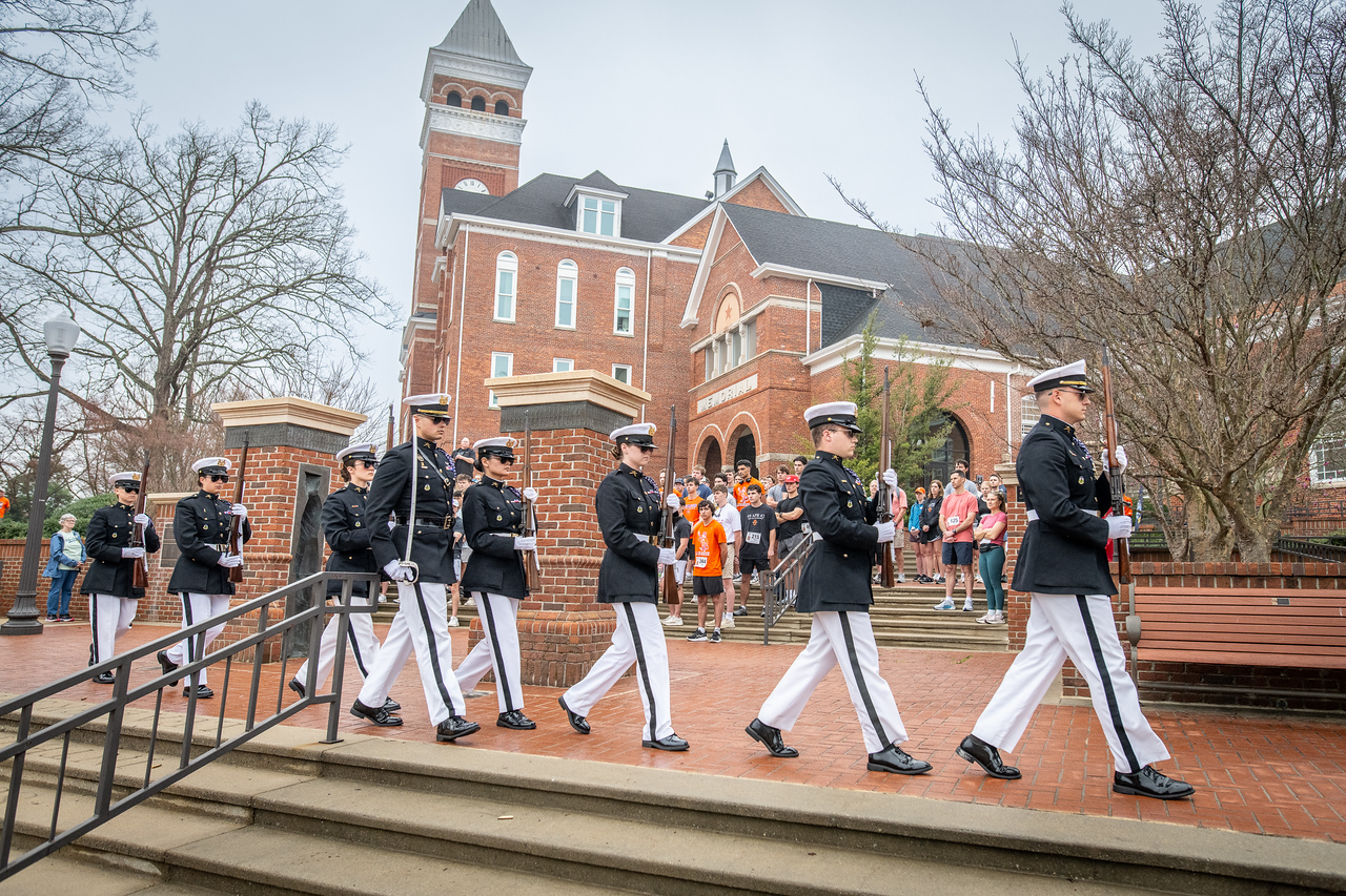 Hundreds of people participate in the 2026 Clemson 8 Challenge, an eight-mile run/walk/ruck march, on a misty Saturday morning, March 7, 2026. The Challenge was created to honor the 25 known Clemson alumni who suffered as POWs in all wars. It was originally created for 1938 Clemson alumnus, professor emeritus and WWII hero Ben Skardon, a survivor of the Bataan Death March, but has expanded to include Clemson POWs from all wars. Money raised from the event goes toward sending teams of Clemson ROTC students to participate in the Bataan Memorial Death March at White Sands Missile Range, NM. Sophomore finance major GB Stalnaker served as master of ceremonies. (Photo by Ken Scar)