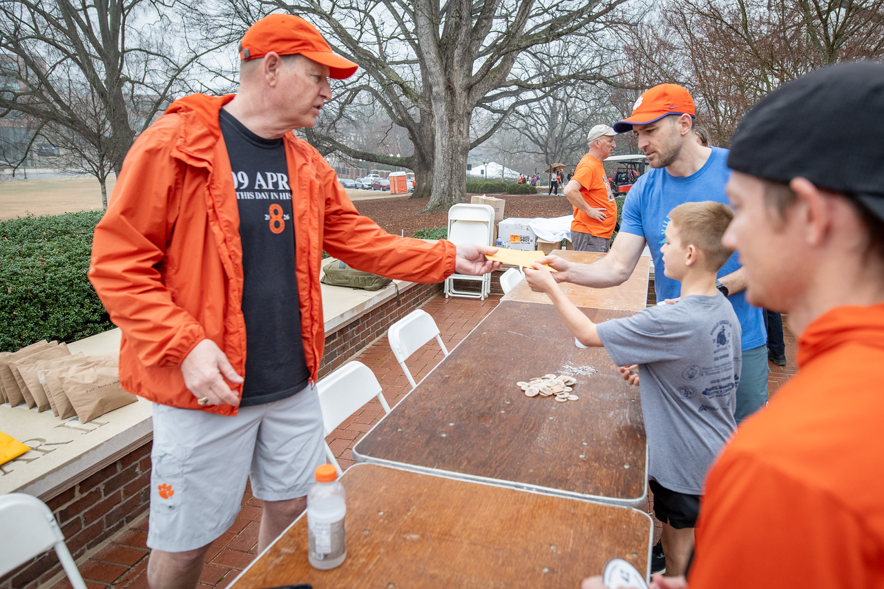 Hundreds of people participate in the 2026 Clemson 8 Challenge, an eight-mile run/walk/ruck march, on a misty Saturday morning, March 7, 2026. The Challenge was created to honor the 25 known Clemson alumni who suffered as POWs in all wars. It was originally created for 1938 Clemson alumnus, professor emeritus and WWII hero Ben Skardon, a survivor of the Bataan Death March, but has expanded to include Clemson POWs from all wars. Money raised from the event goes toward sending teams of Clemson ROTC students to participate in the Bataan Memorial Death March at White Sands Missile Range, NM. Sophomore finance major GB Stalnaker served as master of ceremonies. (Photo by Ken Scar)