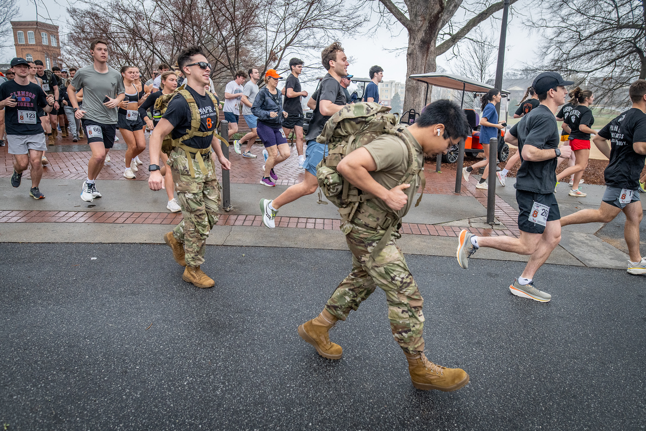 Hundreds of people participate in the 2026 Clemson 8 Challenge, an eight-mile run/walk/ruck march, on a misty Saturday morning, March 7, 2026. The Challenge was created to honor the 25 known Clemson alumni who suffered as POWs in all wars. It was originally created for 1938 Clemson alumnus, professor emeritus and WWII hero Ben Skardon, a survivor of the Bataan Death March, but has expanded to include Clemson POWs from all wars. Money raised from the event goes toward sending teams of Clemson ROTC students to participate in the Bataan Memorial Death March at White Sands Missile Range, NM. Sophomore finance major GB Stalnaker served as master of ceremonies. (Photo by Ken Scar)