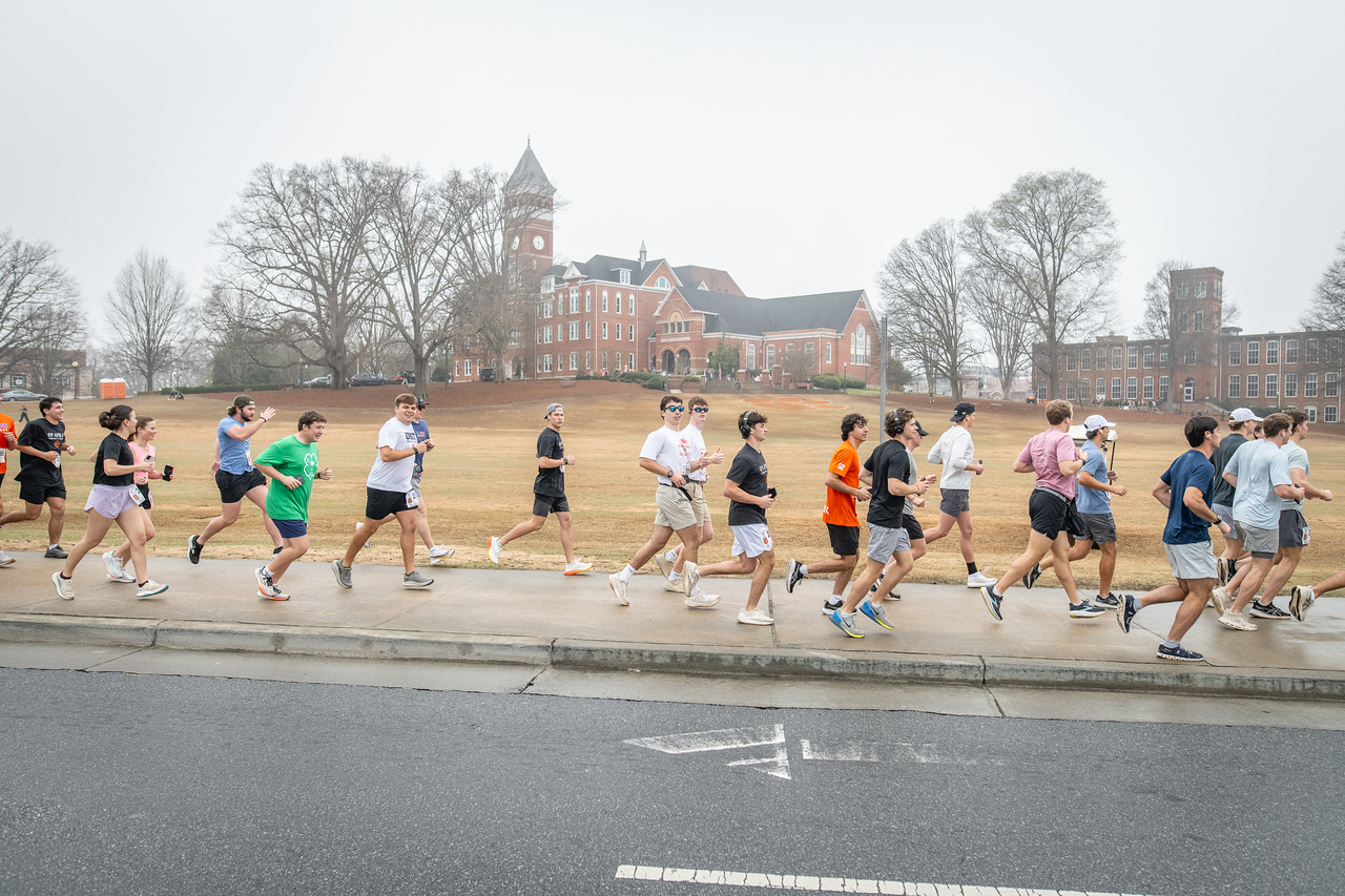 Hundreds of people participate in the 2026 Clemson 8 Challenge, an eight-mile run/walk/ruck march, on a misty Saturday morning, March 7, 2026. The Challenge was created to honor the 25 known Clemson alumni who suffered as POWs in all wars. It was originally created for 1938 Clemson alumnus, professor emeritus and WWII hero Ben Skardon, a survivor of the Bataan Death March, but has expanded to include Clemson POWs from all wars. Money raised from the event goes toward sending teams of Clemson ROTC students to participate in the Bataan Memorial Death March at White Sands Missile Range, NM. Sophomore finance major GB Stalnaker served as master of ceremonies. (Photo by Ken Scar)