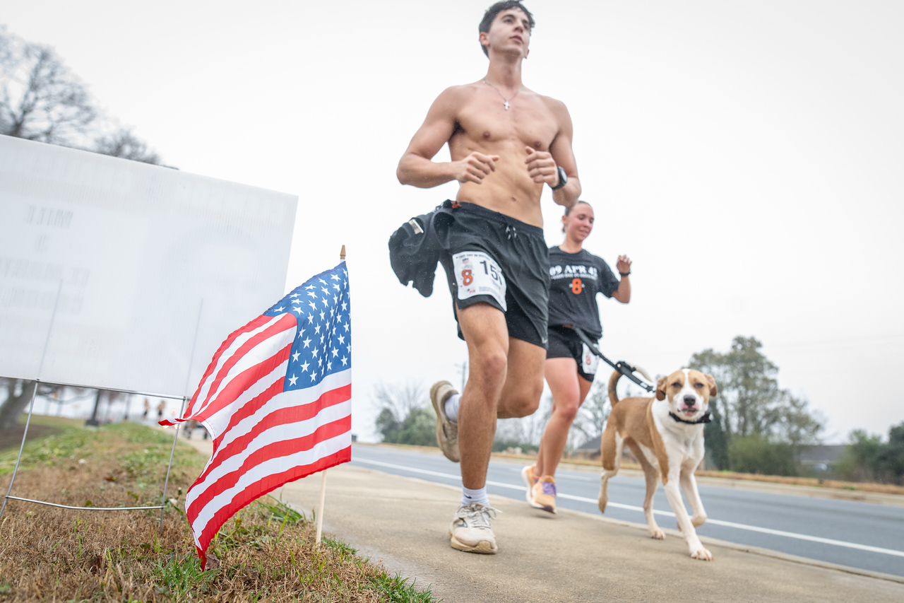 Hundreds of people participate in the 2026 Clemson 8 Challenge, an eight-mile run/walk/ruck march, on a misty Saturday morning, March 7, 2026. The Challenge was created to honor the 25 known Clemson alumni who suffered as POWs in all wars. It was originally created for 1938 Clemson alumnus, professor emeritus and WWII hero Ben Skardon, a survivor of the Bataan Death March, but has expanded to include Clemson POWs from all wars. Money raised from the event goes toward sending teams of Clemson ROTC students to participate in the Bataan Memorial Death March at White Sands Missile Range, NM. Sophomore finance major GB Stalnaker served as master of ceremonies. (Photo by Ken Scar)