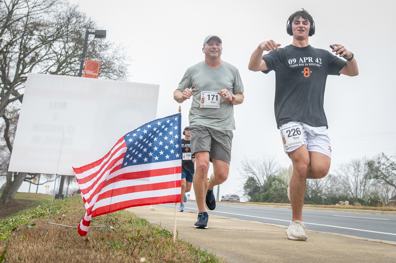 Hundreds of people participate in the 2026 Clemson 8 Challenge, an eight-mile run/walk/ruck march, on a misty Saturday morning, March 7, 2026. The Challenge was created to honor the 25 known Clemson alumni who suffered as POWs in all wars. It was originally created for 1938 Clemson alumnus, professor emeritus and WWII hero Ben Skardon, a survivor of the Bataan Death March, but has expanded to include Clemson POWs from all wars. Money raised from the event goes toward sending teams of Clemson ROTC students to participate in the Bataan Memorial Death March at White Sands Missile Range, NM. Sophomore finance major GB Stalnaker served as master of ceremonies. (Photo by Ken Scar)
