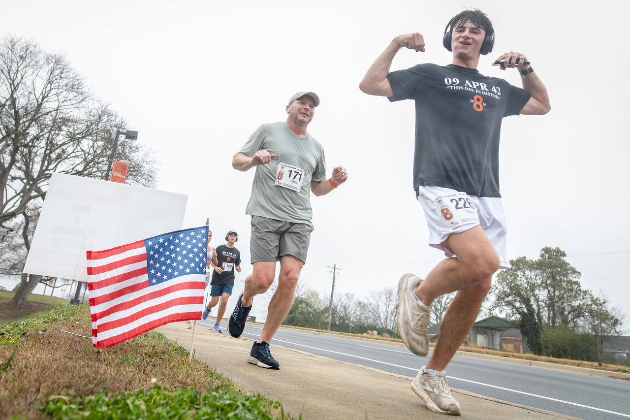 Hundreds of people participate in the 2026 Clemson 8 Challenge, an eight-mile run/walk/ruck march, on a misty Saturday morning, March 7, 2026. The Challenge was created to honor the 25 known Clemson alumni who suffered as POWs in all wars. It was originally created for 1938 Clemson alumnus, professor emeritus and WWII hero Ben Skardon, a survivor of the Bataan Death March, but has expanded to include Clemson POWs from all wars. Money raised from the event goes toward sending teams of Clemson ROTC students to participate in the Bataan Memorial Death March at White Sands Missile Range, NM. Sophomore finance major GB Stalnaker served as master of ceremonies. (Photo by Ken Scar)