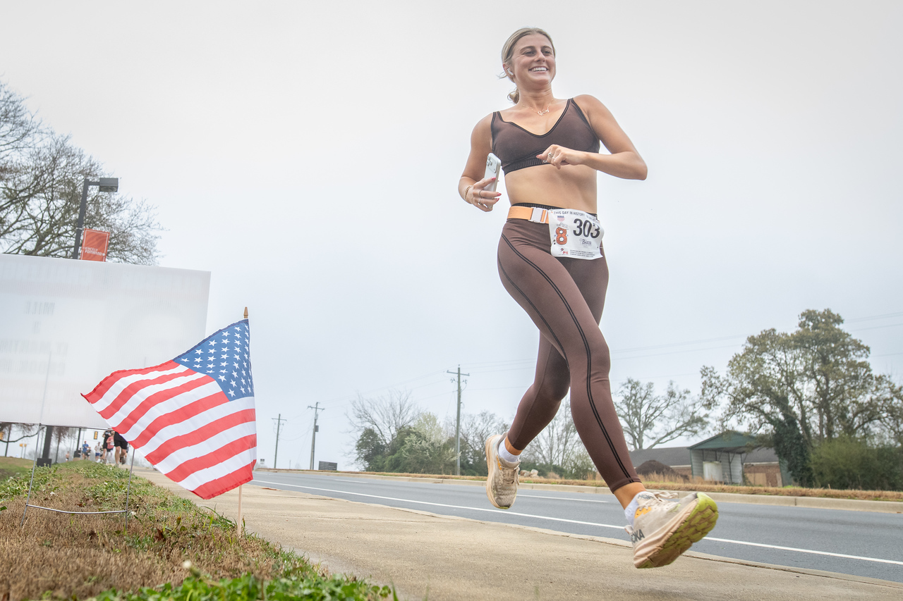 Hundreds of people participate in the 2026 Clemson 8 Challenge, an eight-mile run/walk/ruck march, on a misty Saturday morning, March 7, 2026. The Challenge was created to honor the 25 known Clemson alumni who suffered as POWs in all wars. It was originally created for 1938 Clemson alumnus, professor emeritus and WWII hero Ben Skardon, a survivor of the Bataan Death March, but has expanded to include Clemson POWs from all wars. Money raised from the event goes toward sending teams of Clemson ROTC students to participate in the Bataan Memorial Death March at White Sands Missile Range, NM. Sophomore finance major GB Stalnaker served as master of ceremonies. (Photo by Ken Scar)