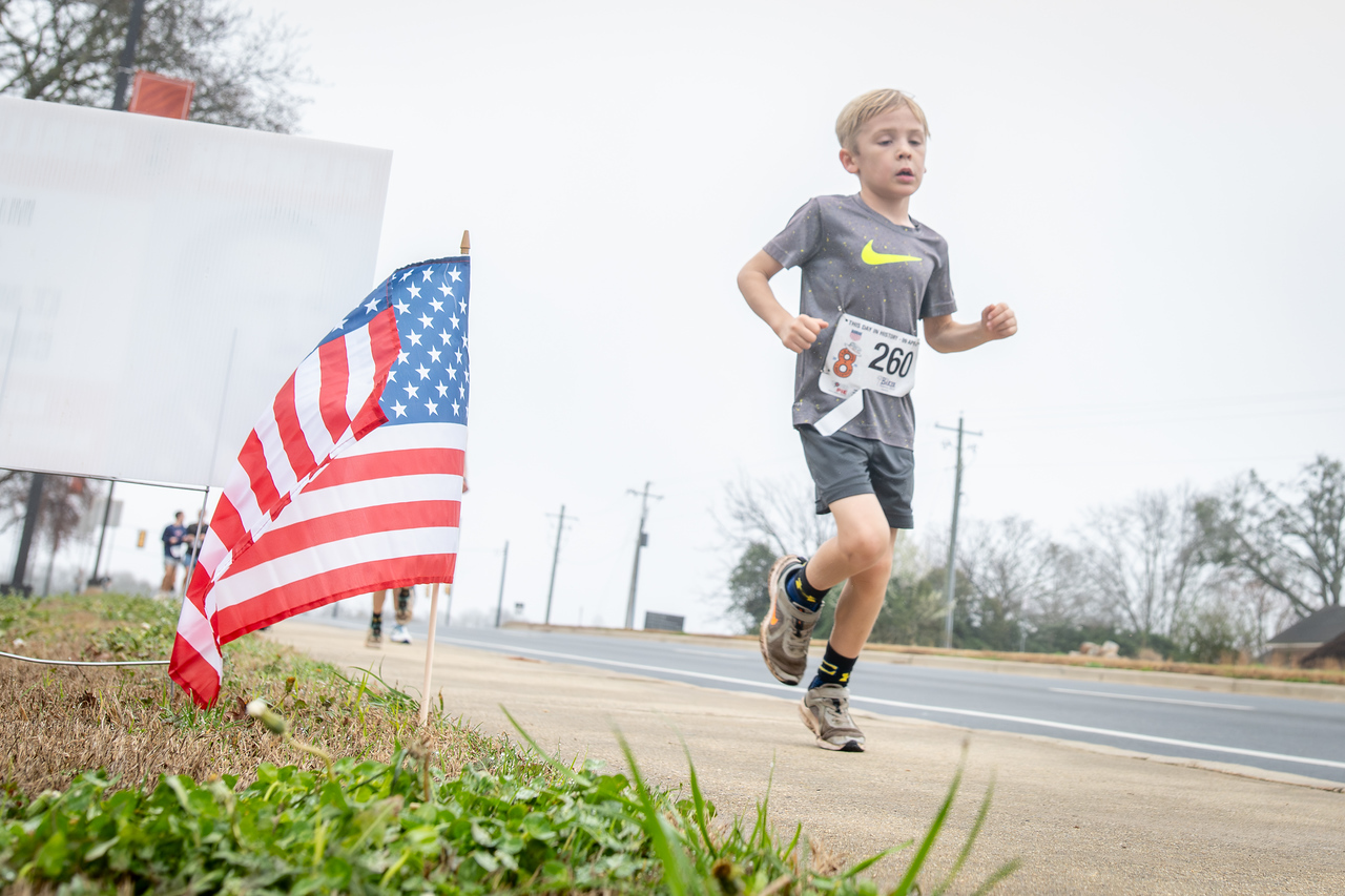 Hundreds of people participate in the 2026 Clemson 8 Challenge, an eight-mile run/walk/ruck march, on a misty Saturday morning, March 7, 2026. The Challenge was created to honor the 25 known Clemson alumni who suffered as POWs in all wars. It was originally created for 1938 Clemson alumnus, professor emeritus and WWII hero Ben Skardon, a survivor of the Bataan Death March, but has expanded to include Clemson POWs from all wars. Money raised from the event goes toward sending teams of Clemson ROTC students to participate in the Bataan Memorial Death March at White Sands Missile Range, NM. Sophomore finance major GB Stalnaker served as master of ceremonies. (Photo by Ken Scar)