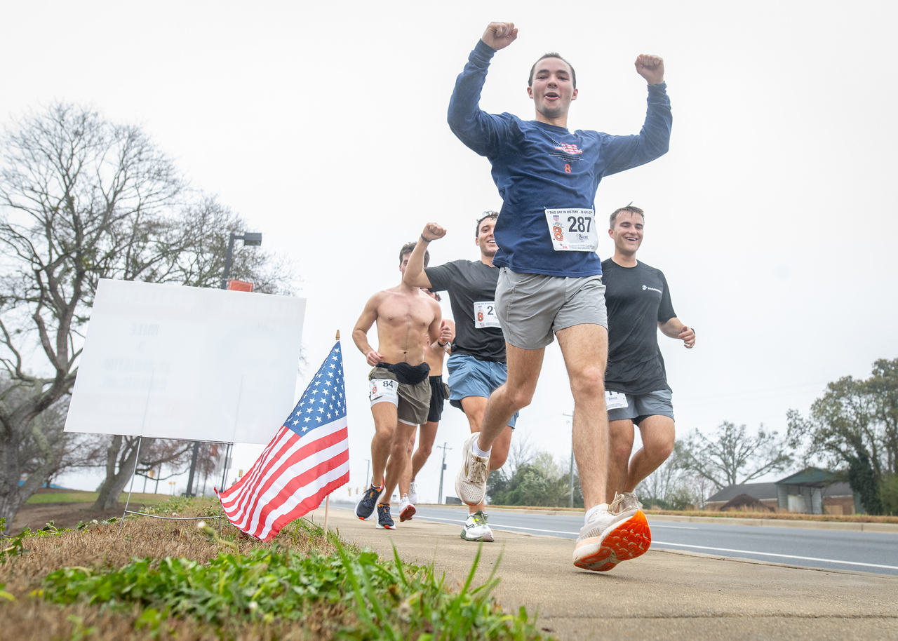 Hundreds of people participate in the 2026 Clemson 8 Challenge, an eight-mile run/walk/ruck march, on a misty Saturday morning, March 7, 2026. The Challenge was created to honor the 25 known Clemson alumni who suffered as POWs in all wars. It was originally created for 1938 Clemson alumnus, professor emeritus and WWII hero Ben Skardon, a survivor of the Bataan Death March, but has expanded to include Clemson POWs from all wars. Money raised from the event goes toward sending teams of Clemson ROTC students to participate in the Bataan Memorial Death March at White Sands Missile Range, NM. Sophomore finance major GB Stalnaker served as master of ceremonies. (Photo by Ken Scar)