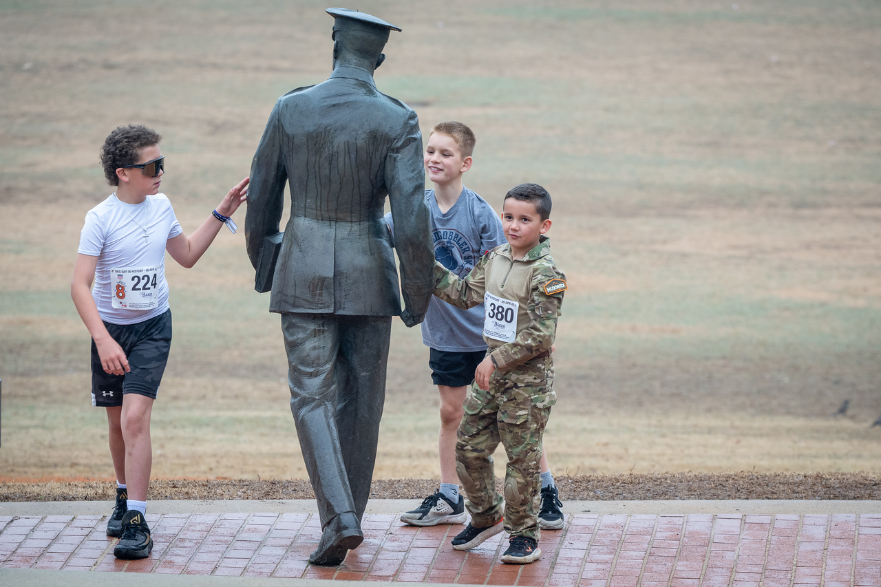 Hundreds of people participate in the 2026 Clemson 8 Challenge, an eight-mile run/walk/ruck march, on a misty Saturday morning, March 7, 2026. The Challenge was created to honor the 25 known Clemson alumni who suffered as POWs in all wars. It was originally created for 1938 Clemson alumnus, professor emeritus and WWII hero Ben Skardon, a survivor of the Bataan Death March, but has expanded to include Clemson POWs from all wars. Money raised from the event goes toward sending teams of Clemson ROTC students to participate in the Bataan Memorial Death March at White Sands Missile Range, NM. Sophomore finance major GB Stalnaker served as master of ceremonies. (Photo by Ken Scar)