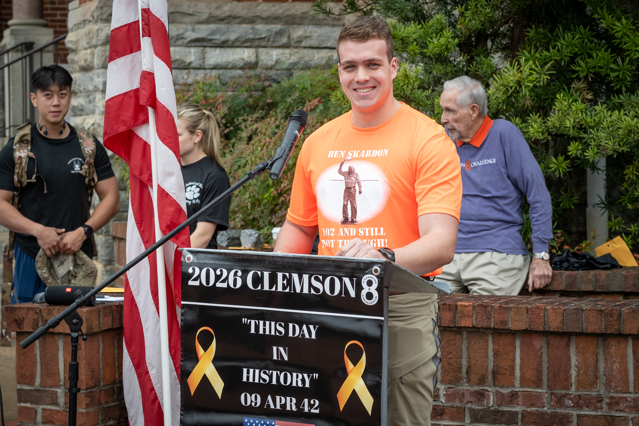 Hundreds of people participate in the 2026 Clemson 8 Challenge, an eight-mile run/walk/ruck march, on a misty Saturday morning, March 7, 2026. The Challenge was created to honor the 25 known Clemson alumni who suffered as POWs in all wars. It was originally created for 1938 Clemson alumnus, professor emeritus and WWII hero Ben Skardon, a survivor of the Bataan Death March, but has expanded to include Clemson POWs from all wars. Money raised from the event goes toward sending teams of Clemson ROTC students to participate in the Bataan Memorial Death March at White Sands Missile Range, NM. Sophomore finance major GB Stalnaker served as master of ceremonies. (Photo by Ken Scar)