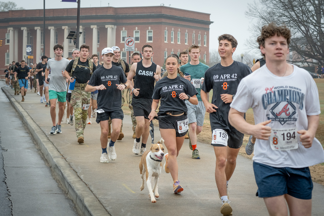 Hundreds of people participate in the 2026 Clemson 8 Challenge, an eight-mile run/walk/ruck march, on a misty Saturday morning, March 7, 2026. The Challenge was created to honor the 25 known Clemson alumni who suffered as POWs in all wars. It was originally created for 1938 Clemson alumnus, professor emeritus and WWII hero Ben Skardon, a survivor of the Bataan Death March, but has expanded to include Clemson POWs from all wars. Money raised from the event goes toward sending teams of Clemson ROTC students to participate in the Bataan Memorial Death March at White Sands Missile Range, NM. Sophomore finance major GB Stalnaker served as master of ceremonies. (Photo by Ken Scar)