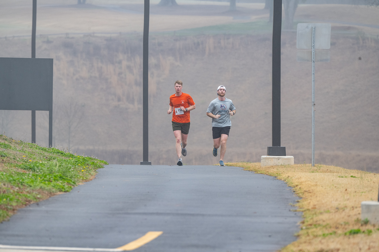 Hundreds of people participate in the 2026 Clemson 8 Challenge, an eight-mile run/walk/ruck march, on a misty Saturday morning, March 7, 2026. The Challenge was created to honor the 25 known Clemson alumni who suffered as POWs in all wars. It was originally created for 1938 Clemson alumnus, professor emeritus and WWII hero Ben Skardon, a survivor of the Bataan Death March, but has expanded to include Clemson POWs from all wars. Money raised from the event goes toward sending teams of Clemson ROTC students to participate in the Bataan Memorial Death March at White Sands Missile Range, NM. Sophomore finance major GB Stalnaker served as master of ceremonies. (Photo by Ken Scar)