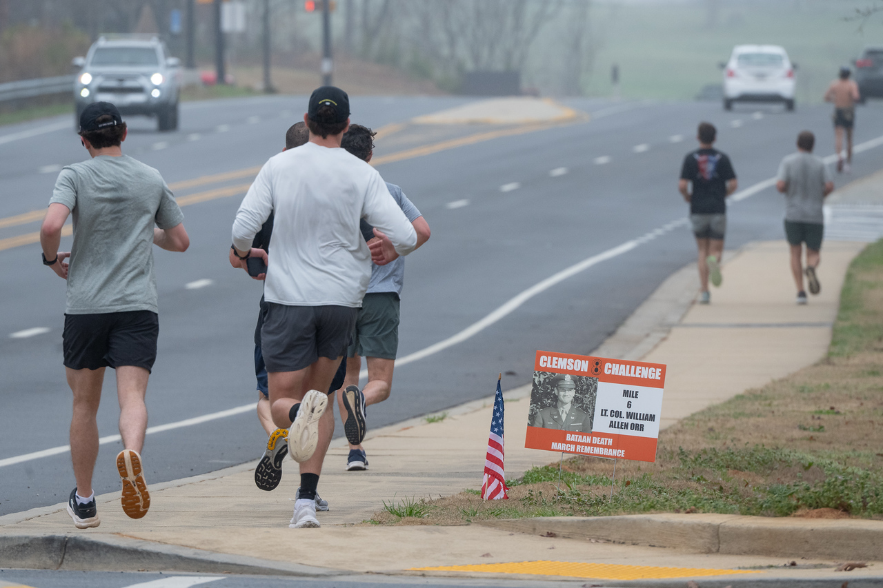 Hundreds of people participate in the 2026 Clemson 8 Challenge, an eight-mile run/walk/ruck march, on a misty Saturday morning, March 7, 2026. The Challenge was created to honor the 25 known Clemson alumni who suffered as POWs in all wars. It was originally created for 1938 Clemson alumnus, professor emeritus and WWII hero Ben Skardon, a survivor of the Bataan Death March, but has expanded to include Clemson POWs from all wars. Money raised from the event goes toward sending teams of Clemson ROTC students to participate in the Bataan Memorial Death March at White Sands Missile Range, NM. Sophomore finance major GB Stalnaker served as master of ceremonies. (Photo by Ken Scar)