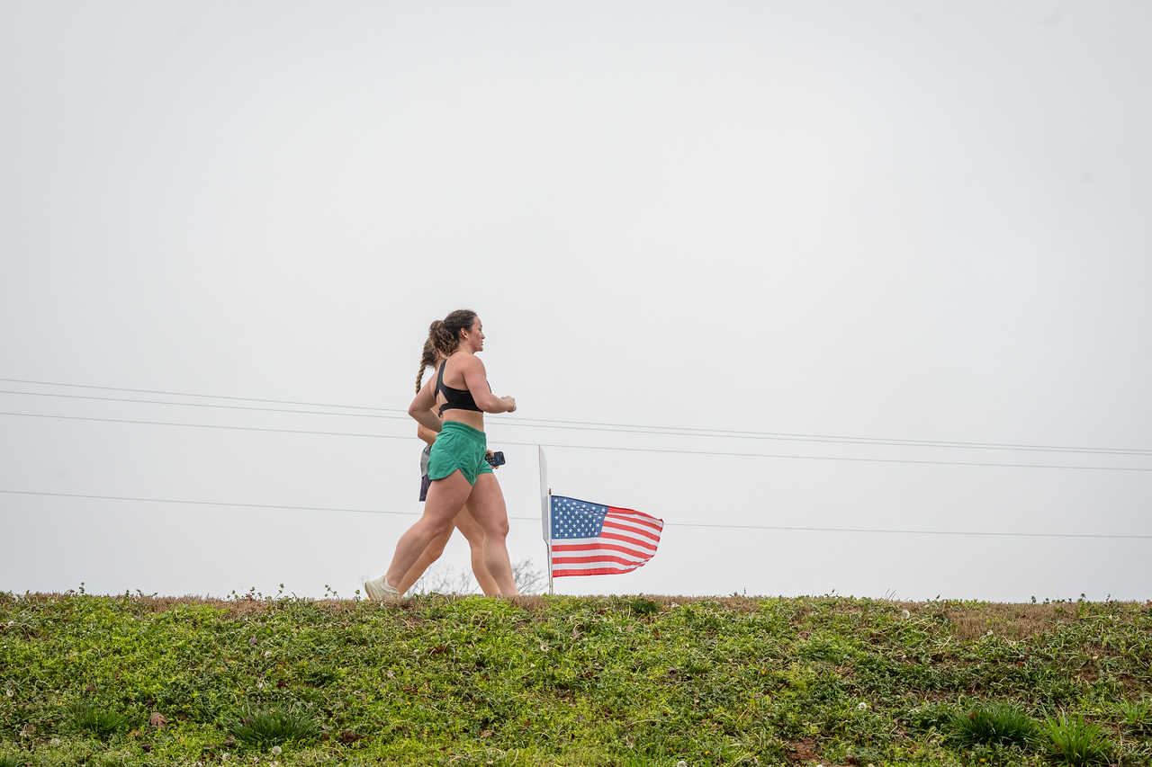 Hundreds of people participate in the 2026 Clemson 8 Challenge, an eight-mile run/walk/ruck march, on a misty Saturday morning, March 7, 2026. The Challenge was created to honor the 25 known Clemson alumni who suffered as POWs in all wars. It was originally created for 1938 Clemson alumnus, professor emeritus and WWII hero Ben Skardon, a survivor of the Bataan Death March, but has expanded to include Clemson POWs from all wars. Money raised from the event goes toward sending teams of Clemson ROTC students to participate in the Bataan Memorial Death March at White Sands Missile Range, NM. Sophomore finance major GB Stalnaker served as master of ceremonies. (Photo by Ken Scar)