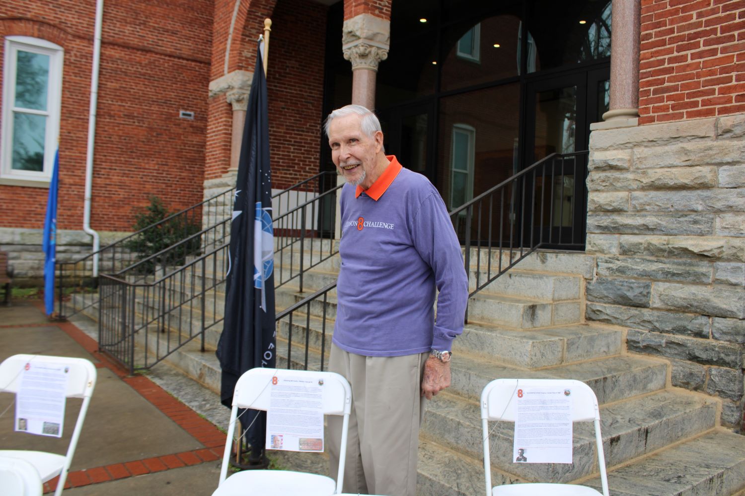 Colonel Bill Austin beside a chair with a dog tag with his name at the Clemson 8 Challenge (Photo by Karen Brewer, The Pickens County Chronicle)