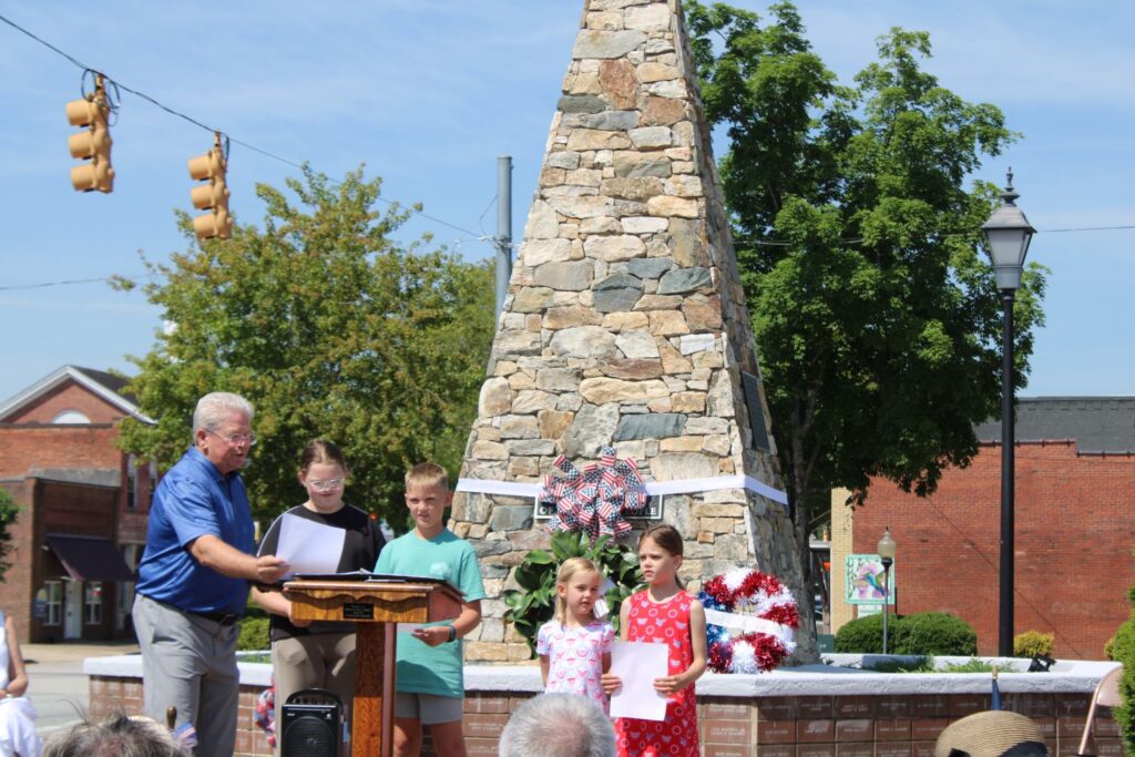 Bryan Hester, Minister of Music of Pickens First Baptist Church, and children from Pickens First Baptist Church (brother and sister Anna and J.P. Shipman and sisters Caroline and Catherine Chapman) sing "My Country, 'Tis of Thee" (Photo by Karen Brewer, The Pickens County Chronicle)